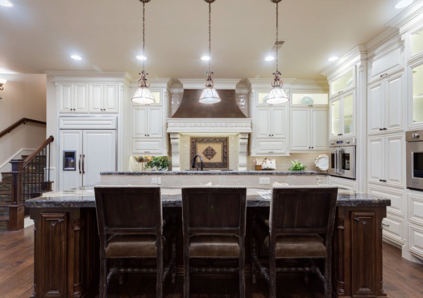 A prosper rental property is pictured with the kitchen in frame, white cupboards, overhead lighting and dark brown wood.